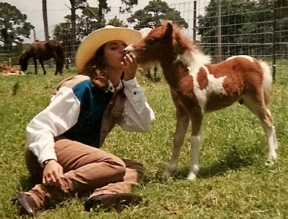 Girl kissing miniature horse foal in 1989